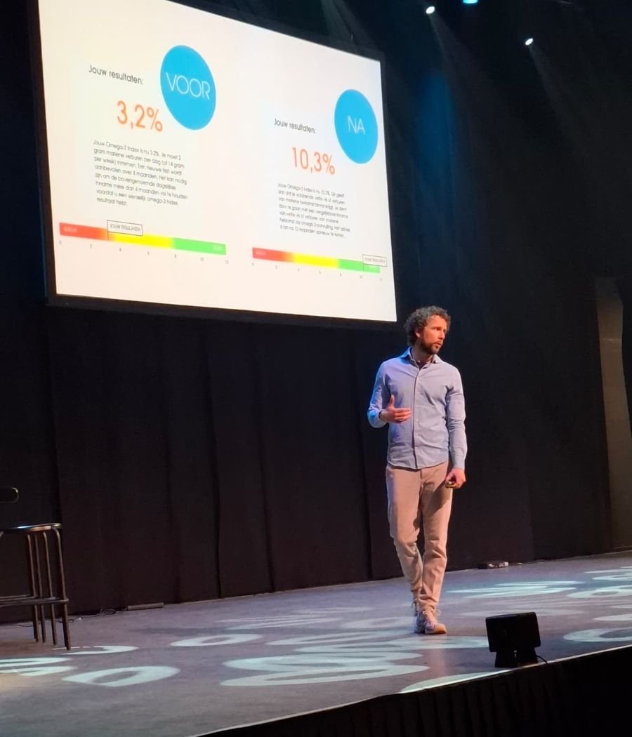 Hans geeft een lezing en laat op een groot scherm meetresultaten van voor en na zien
